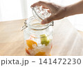 ホワイトリカーと完熟梅と氷砂糖の入った瓶の蓋を閉めている 141472230
