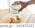 ホワイトリカーと完熟梅と氷砂糖の入った瓶の蓋を閉めている 141472231