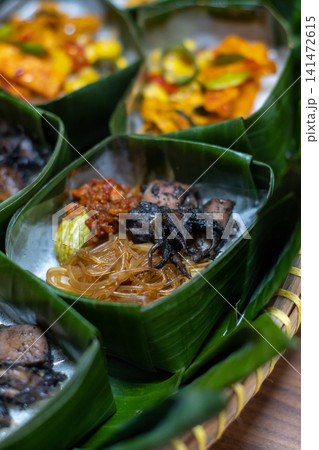 Traditional Indonesian Rice Meal in Banana Leaf Takir with Black Ink Squid, Vermicelli and Sambal, Authentic Seafood Cuisine, Eco Friendly Food Packaging, Nusantara Culinary Traditional Indonesian Rice Meal in Banana Leaf Takir with Black Ink Squid, Vermicelli and Sambal, Authentic Seafood Cuisine, Eco Friendly Food Packaging, Nusantara Culinary 141472615