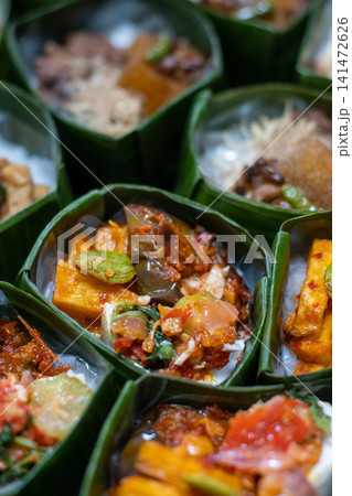 Traditional Indonesian Rice Meal in Banana Leaf Takir with Spicy Tofu, Sambal and Assorted Vegetables, Authentic Nusantara Cuisine, Eco Friendly Food Presentation Traditional Indonesian Rice Meal in Banana Leaf Takir with Spicy Tofu, Sambal and Assorted Vegetables, Authentic Nusantara Cuisine, Eco Friendly Food Presentation 141472626