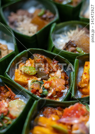 Traditional Indonesian Rice Meal in Banana Leaf Takir with Spicy Tofu, Sambal and Assorted Vegetables, Authentic Nusantara Cuisine, Eco Friendly Food Presentation Traditional Indonesian Rice Meal in Banana Leaf Takir with Spicy Tofu, Sambal and Assorted Vegetables, Authentic Nusantara Cuisine, Eco Friendly Food Presentation 141472627