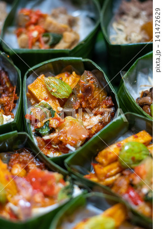 Traditional Indonesian Rice Meal in Banana Leaf Takir with Spicy Tofu, Sambal and Assorted Vegetables, Authentic Nusantara Cuisine, Eco Friendly Food Presentation Traditional Indonesian Rice Meal in Banana Leaf Takir with Spicy Tofu, Sambal and Assorted Vegetables, Authentic Nusantara Cuisine, Eco Friendly Food Presentation 141472629
