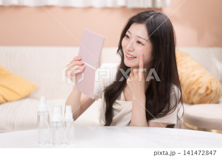鏡を見ながらスキンケアをする若い女性 141472847