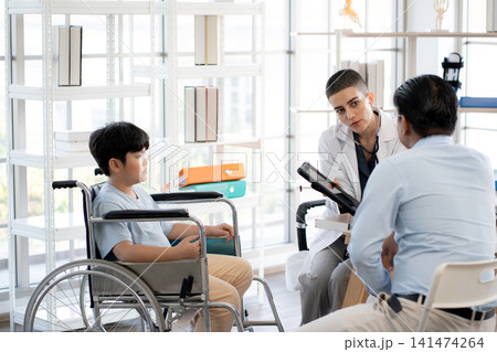 Woman doctor explaining treatment advice with father of child patient in clinic looking at tablet. Woman doctor explaining treatment advice with father of child patient in clinic looking at tablet. 141474264