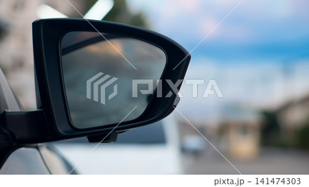 Close up side view of a vehicle's side mirror reflecting traffic on a highway. During a bright day capturing motion and refreshing and cheerful travel experience. 141474303