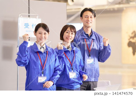 イベント会場の受付前でガッツポーズをする男女スタッフ3人 141474570