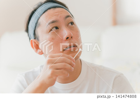 綿棒でリップクリームをつける40代男性 綿棒でリップクリームをつける40代男性 141474808