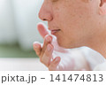 唇にリップクリームを塗る40代男性 141474813