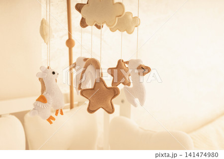 Soft toys dangle from a charming mobile in a peaceful nursery Soft toys dangle from a charming mobile in a peaceful nursery 141474980