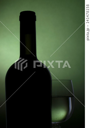 Still life with a bottle and a glass of wine on a green background Still life with a bottle and a glass of wine on a green background 141478158