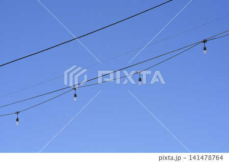 String lights hanging on cables against blue sky String lights hanging on cables against blue sky 141478764