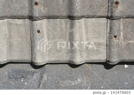 Old concrete roof tiles edge on a textured surface 141478803