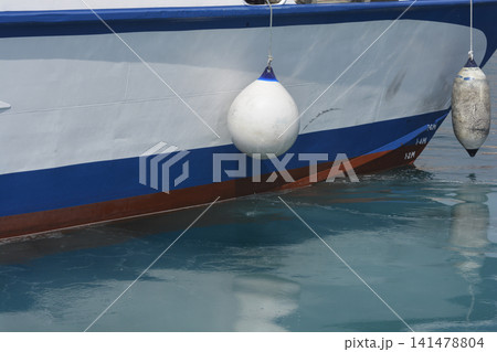 Side view of a white and blue boat hull with fenders 141478804