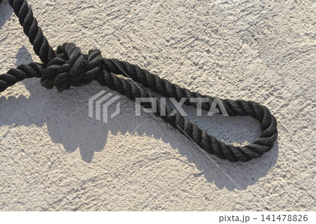 Black marine mooring rope loop with knot on concrete background Black marine mooring rope loop with knot on concrete background 141478826