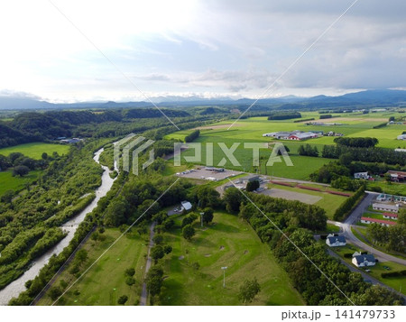 日本・北海道・十勝平野の鹿追町と山並み、農地や草原を望む空撮風景 141479733