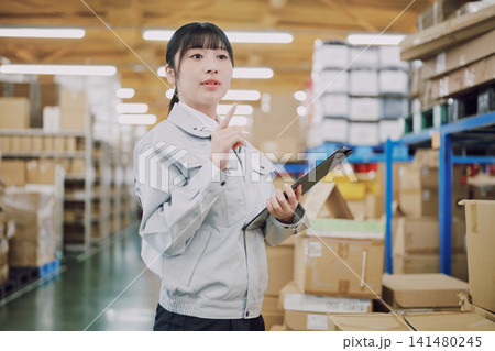 倉庫で在庫管理をする作業服の女性 倉庫で在庫管理をする作業服の女性 141480245