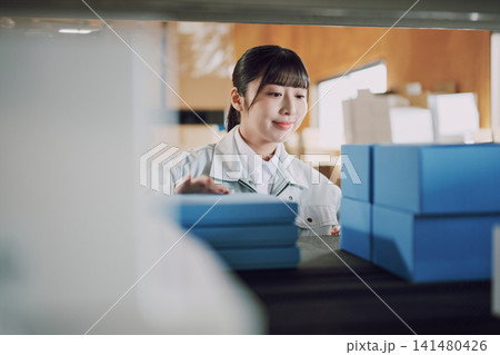 倉庫で在庫管理をする作業服の女性 倉庫で在庫管理をする作業服の女性 141480426