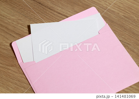 Pink envelope with blank white cards on a wooden table surface 141481069
