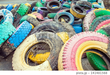 Pile of old multicolored car tires dug in playgrounds. Multicolor used tires. various sizes colored tires. Pile of old multicolored car tires dug in playgrounds. Multicolor used tires. various sizes colored tires. 141481388