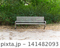 Modern metal bench in the park against green bushes 141482093