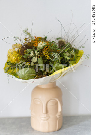 Bouquet of dried flowers in an original ceramic face vase Bouquet of dried flowers in an original ceramic face vase 141482095