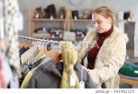 While shopping, teen girl browsing goods items and choose elect something warm outerwear in store While shopping, teen girl browsing goods items and choose elect something warm outerwear in store 141482125