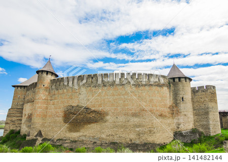 View of old castle Hotin near the river. Khotyn Fortress - medieval castle on yellow autumn hills. Ukraine, Eastern Europe. The architecture of the Middle Ages in our time. 141482144