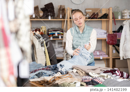Selective teen girl choosing jean pantaloons in clothing store Selective teen girl choosing jean pantaloons in clothing store 141482199