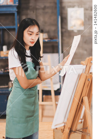 Female artist wears black hat posing near picture indoor the studio 141482600