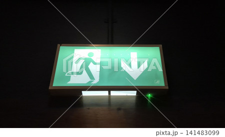 Illuminated emergency exit sign in dark interior 141483099