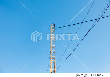Concrete Utility Pole with Overhead Cables Against Blue Sky Concrete Utility Pole with Overhead Cables Against Blue Sky 141484792