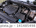 Car engine bay with open hood and battery 141485498