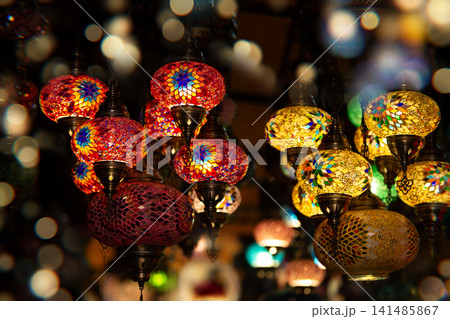 Colorful decorative lanterns illuminate a marketplace filled with vibrant patterns and warm light during an evening setting 141485867