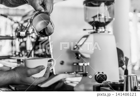 Barista making a Cappuccino coffee in modern coffeeshop with professional equipment  BW Black and White stock photo 141486121