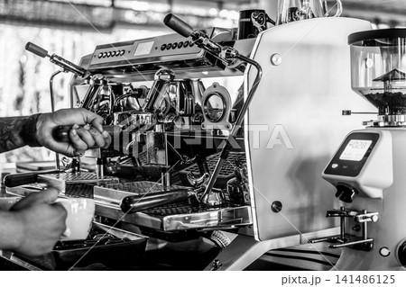 Barista making a Cappuccino coffee in modern coffeeshop with professional equipment BW Black and White stock photo Barista making a Cappuccino coffee in modern coffeeshop with professional equipment BW Black and White stock photo 141486125