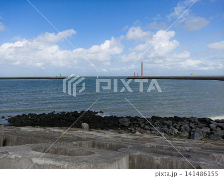 Calm Harbor Entrance With Breakwater, Lighthouses and Sailboat Under Blue Sky and Clouds Calm Harbor Entrance With Breakwater, Lighthouses and Sailboat Under Blue Sky and Clouds 141486155