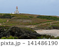 Solitary White Lighthouse on Rugged Coastal Cliffs Overlooking Rocky Beach and Rolling Moorland 141486190