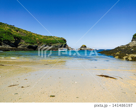 Sunny Sandy Beach Cove With Boats, Rocky Cliffs and Clear Blue Sea on a Summer Day Sunny Sandy Beach Cove With Boats, Rocky Cliffs and Clear Blue Sea on a Summer Day 141486197