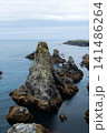 Rugged Sea Stacks and Rocky Coastline Under Overcast Sky With Calm Blue Ocean Horizon 141486264