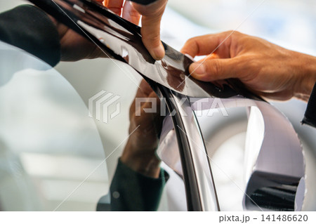 A car wrapping specialist applies a polyurethane film to the car. Detailer PPF A car wrapping specialist applies a polyurethane film to the car. Detailer PPF 141486620