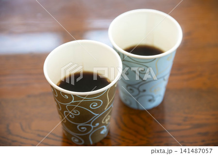 木製テーブルに並ぶ装飾的な紙コップに入ったコーヒー 木製テーブルに並ぶ装飾的な紙コップに入ったコーヒー 141487057
