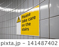 Warning sign on tiled subway wall reading take care on stairs 141487402