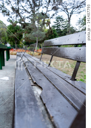 Long, aged wooden park bench in a square on a winter day Long, aged wooden park bench in a square on a winter day 141487793