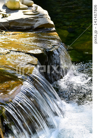 The view of the waterfall in a public park. Splashing Water, water flowing. Nature concept. The view of the waterfall in a public park. Splashing Water, water flowing. Nature concept. 141487806