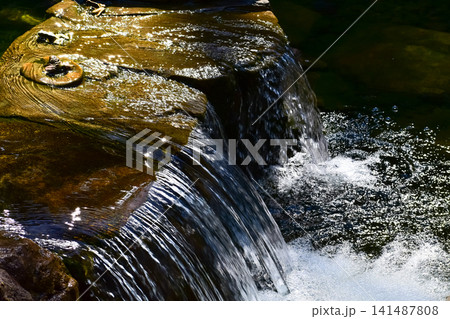 The view of the waterfall in a public park. Splashing Water, water flowing. Nature concept. The view of the waterfall in a public park. Splashing Water, water flowing. Nature concept. 141487808