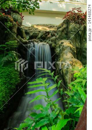 The view of the waterfall in a public park. Splashing Water, water flowing. Nature concept. The view of the waterfall in a public park. Splashing Water, water flowing. Nature concept. 141488274
