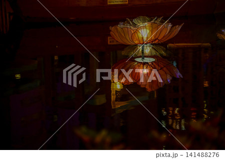 Water reflection of the artificial flower lantern in the pool in the public park at night. Lighting decoration. Festive decoration. Water reflection of the artificial flower lantern in the pool in the public park at night. Lighting decoration. Festive decoration. 141488276