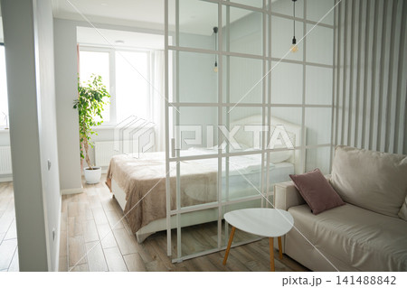 Modern bedroom with elegant divider and minimalist decor in a vacation rental. Interior design real estate and home staging concepts Modern bedroom with elegant divider and minimalist decor in a vacation rental. Interior design real estate and home staging concepts 141488842