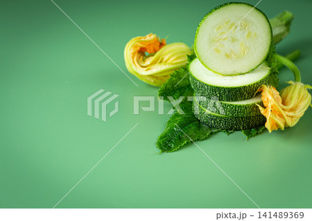 Organic zucchini slices with fresh leaves on pastel green background Organic zucchini slices with fresh leaves on pastel green background 141489369
