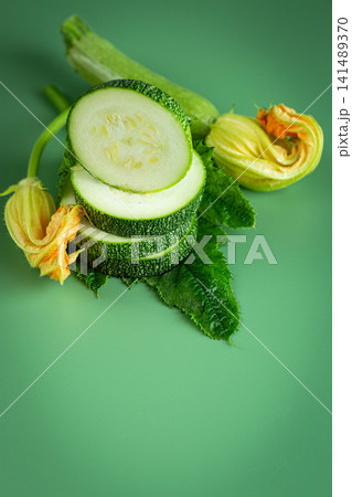 Healthy green zucchini with edible flowers on smooth green background Healthy green zucchini with edible flowers on smooth green background 141489370